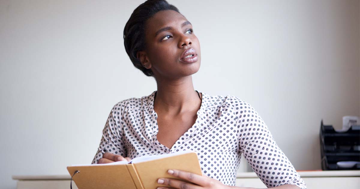 black lady holding a notebook thinking