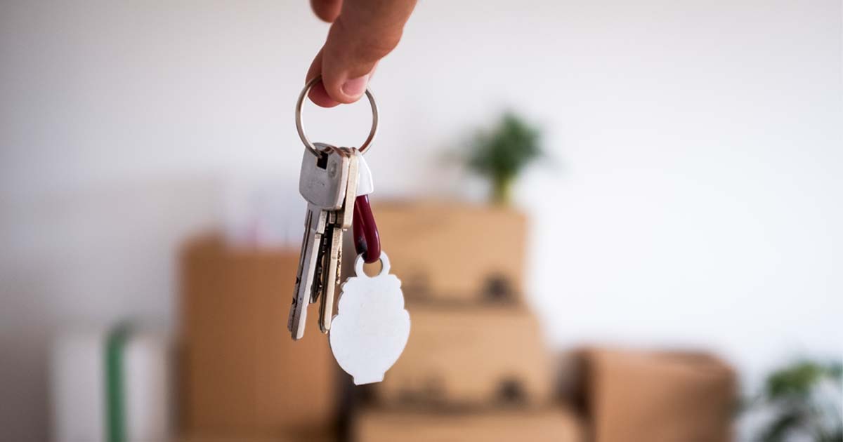 Close up photo of keys to a home. Moving boxes are seen in the background
