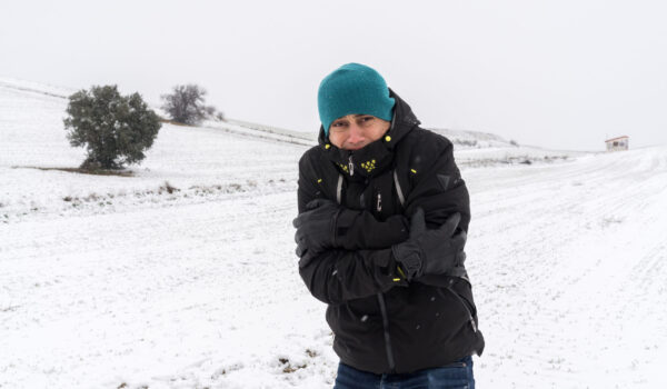 Very cold man in the middle of a snowfall.