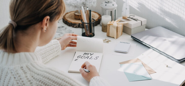 New year resolution, New goals, Start new year, planning and setting goals for the next year. Woman in white sweater writing handwritten text My Goals in open notepad on the table