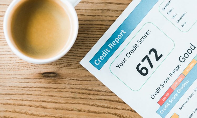 top view of cup with coffee near paper with credit report lettering on paper