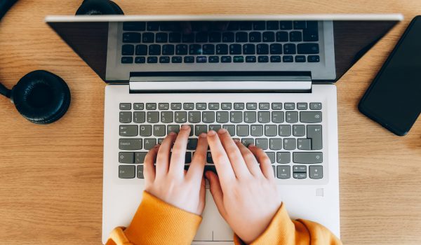 School age girl is home schooling using laptop during self isolation at her bedroom, online education, doing homework