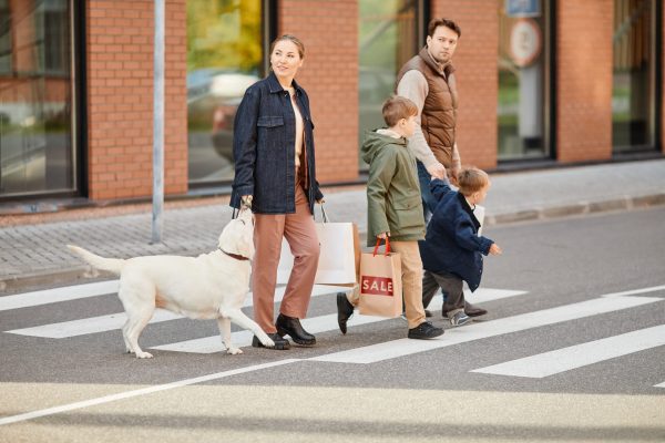 Full length portrait of modern big family leaving shopping mall holding paper bags, copy space