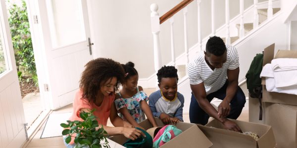 Front view of an African American couple with her son and daughter at home, unpacking boxes in a hallway. Family enjoying time at home, lifestyle concept