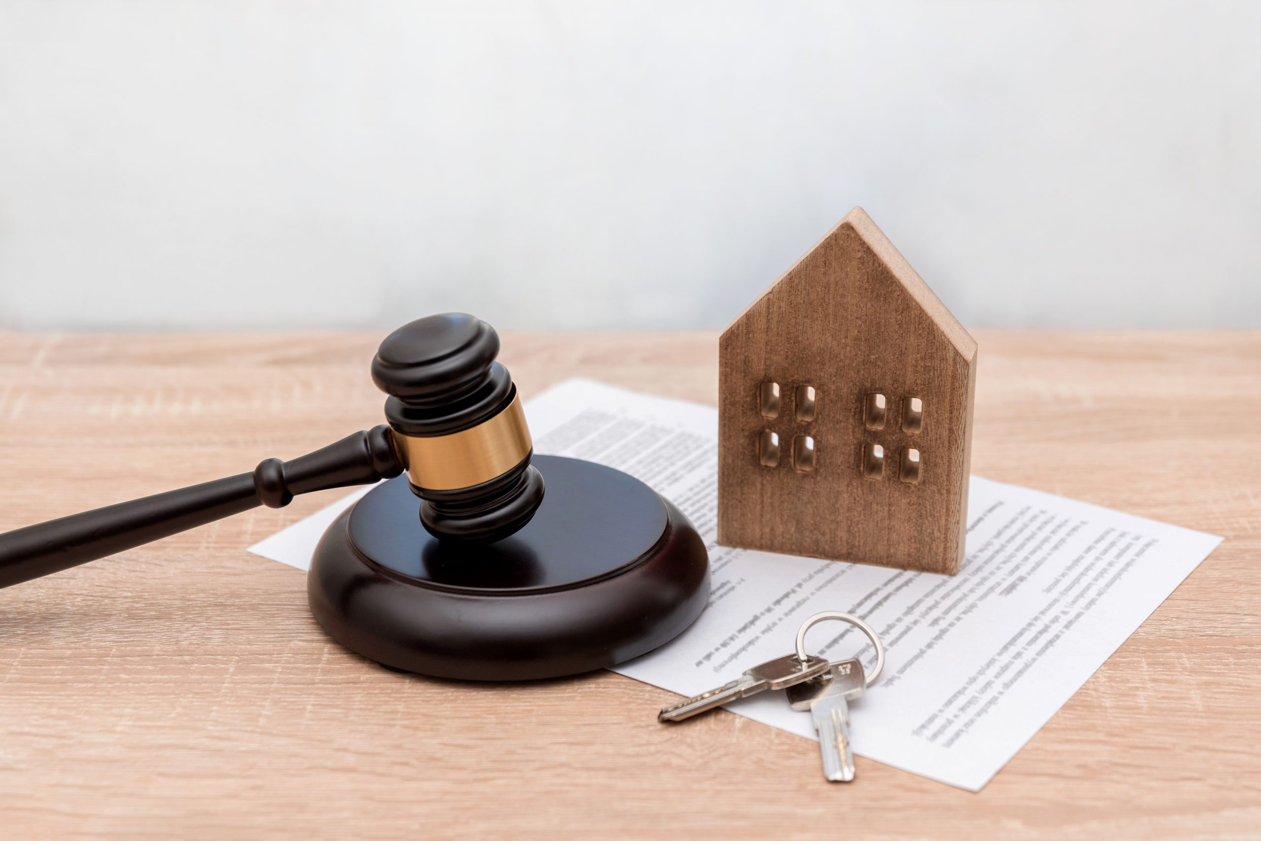 Wooden House Model ,Judge's Gavel, keys and Legal Document on Table, real estate law or property contract
