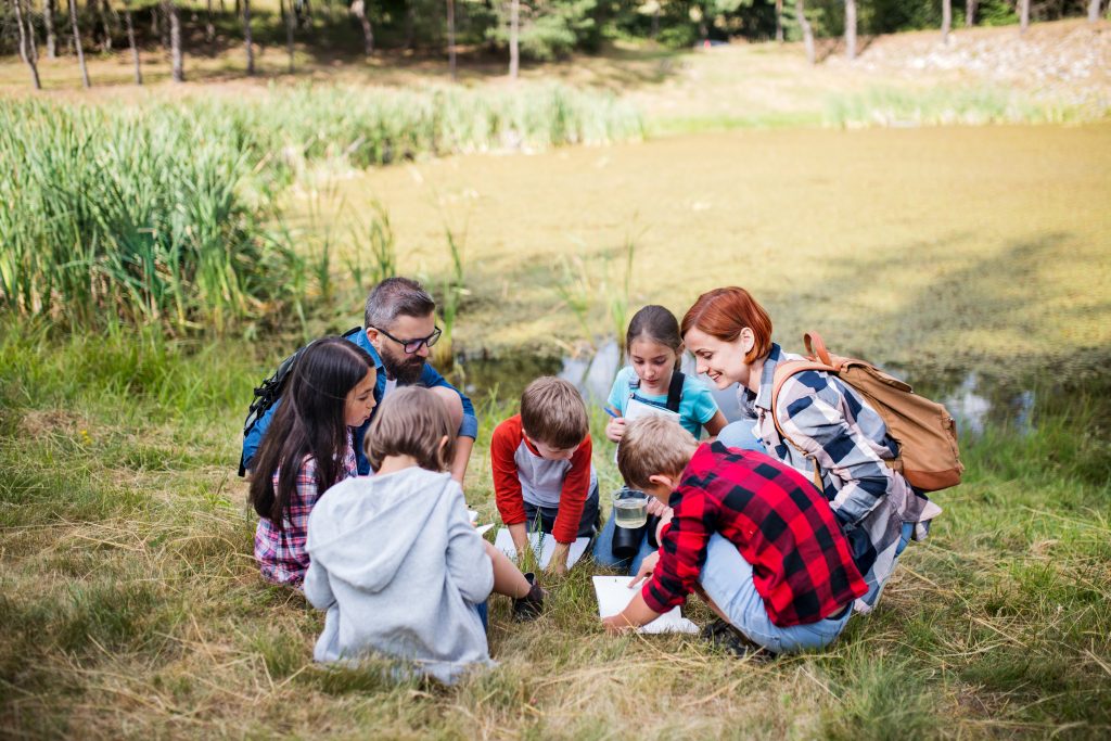 Group of school children with teacher on field trip in nature.
